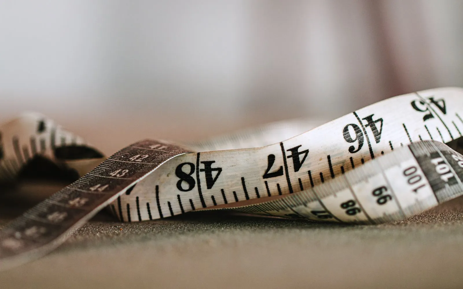 A white fabric tape measure lying in loose curls on a dark surface.