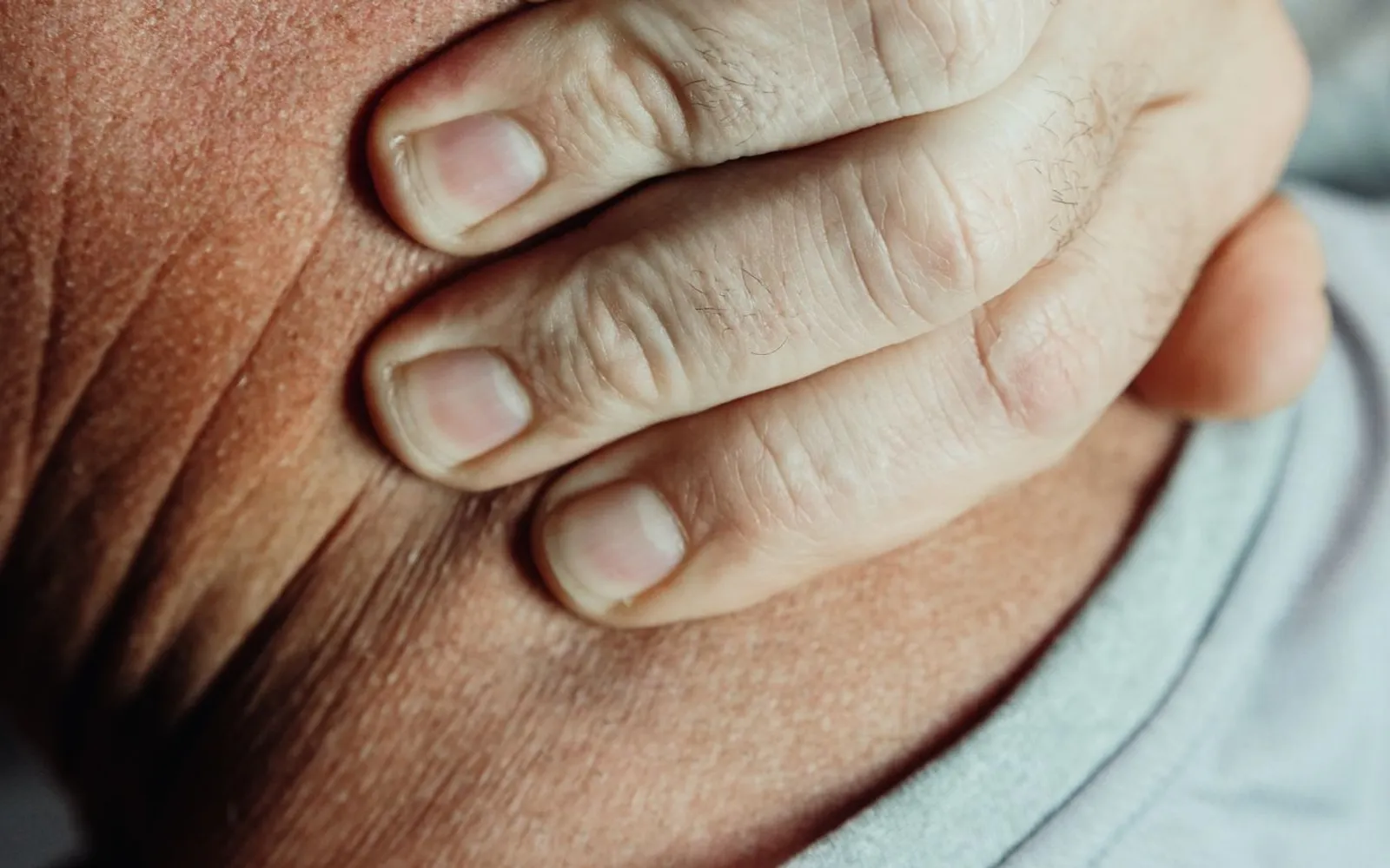 Close-up of a hand holding the back of a person's neck