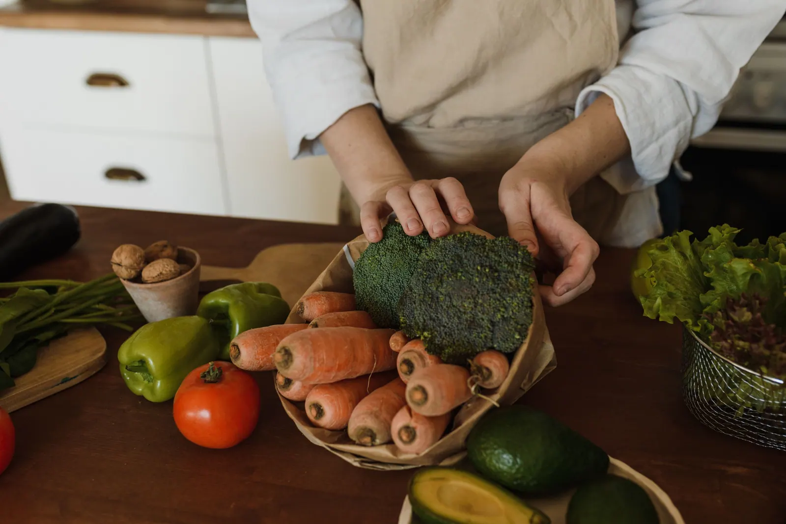 Hands arranging broccoli, carrots and other vegetables.