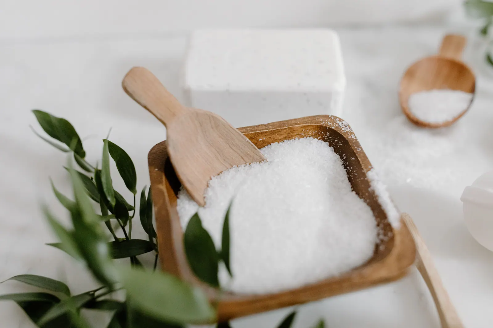 Coarse salt in a wooden bowl with a wooden scoop.