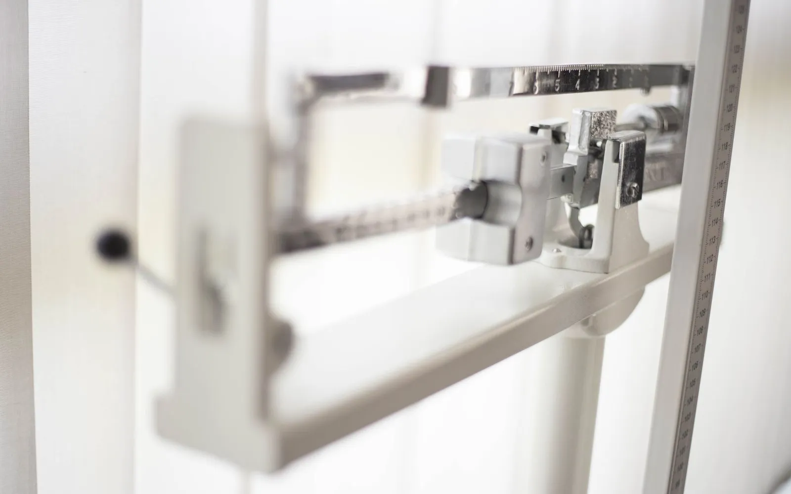 Close-up of a white beam weighing scale with a height measure in a doctor's office.