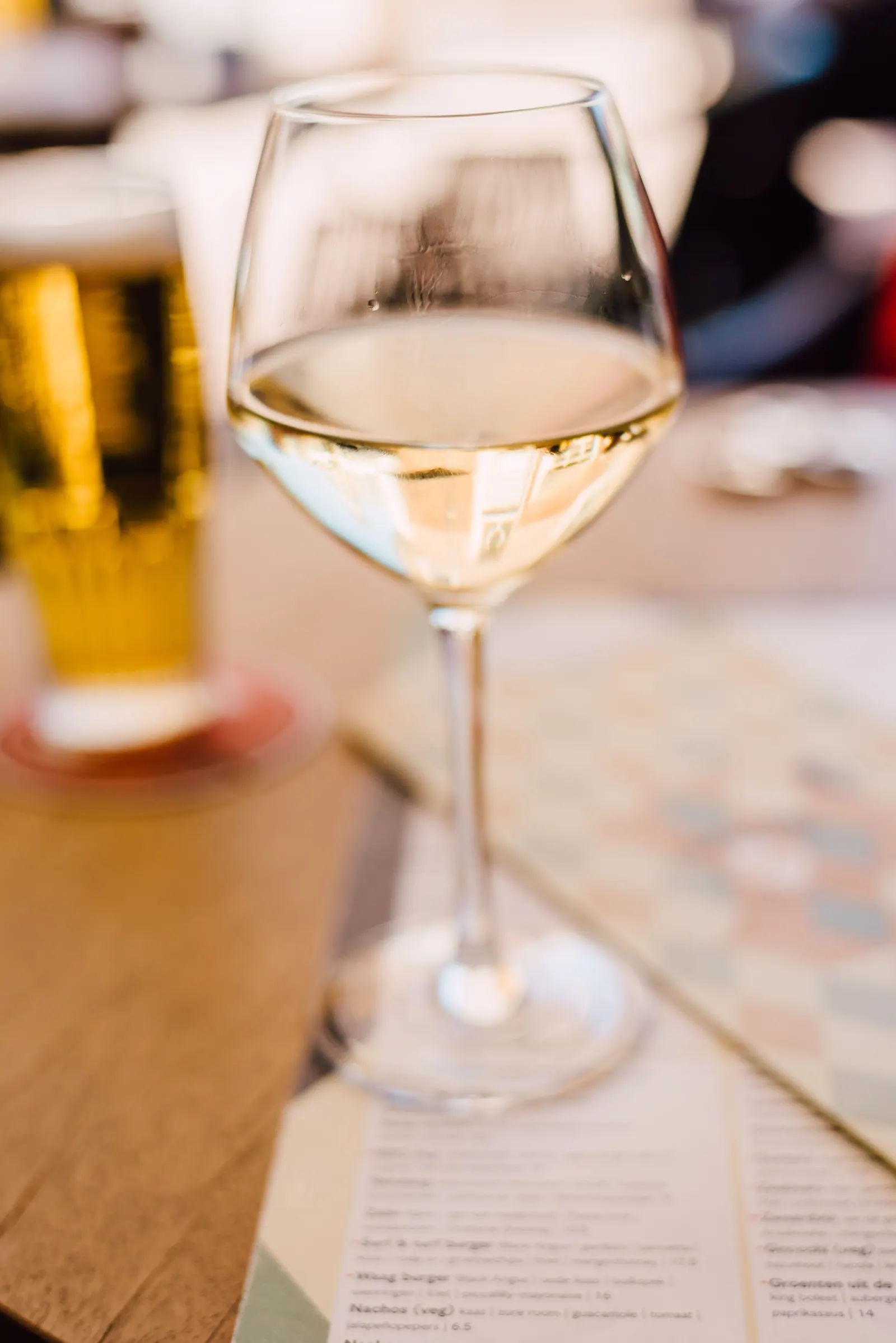 A wine glass on a table, with other drinks in the background.