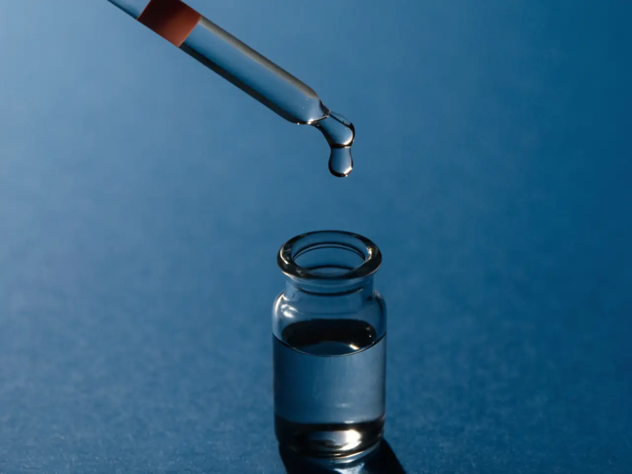 A precision pipette releasing a single drop into a sample vial