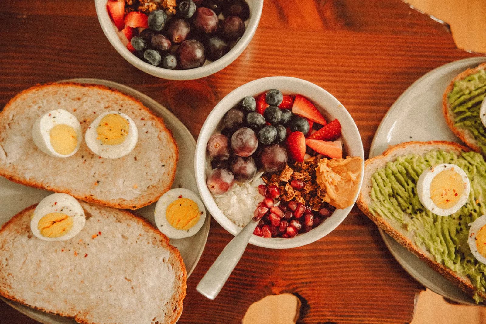 Breakfast with a fruit bowl, eggs and avocado toast.