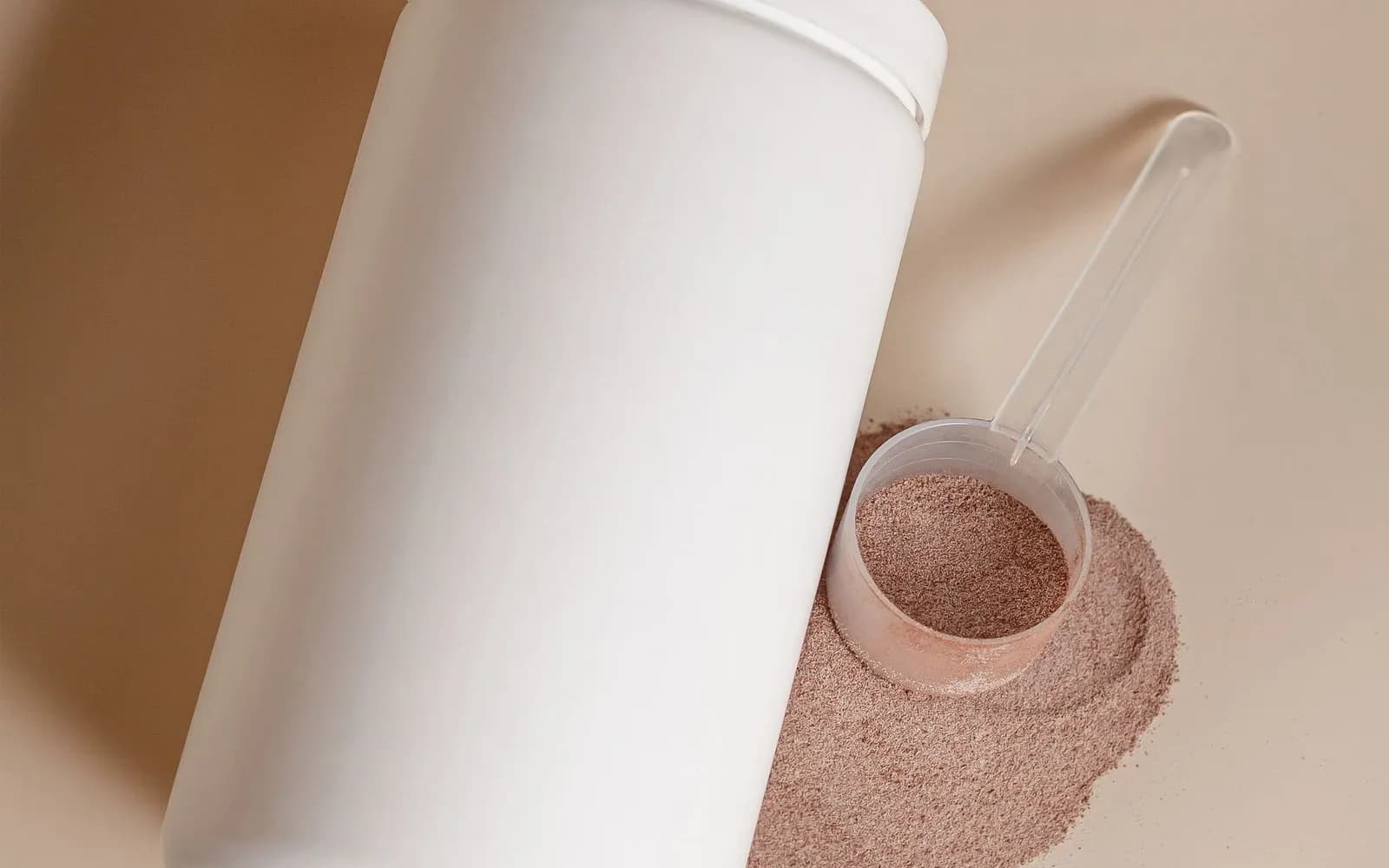 A plain white tub with no label lying beside a measuring scoop of light brown powder