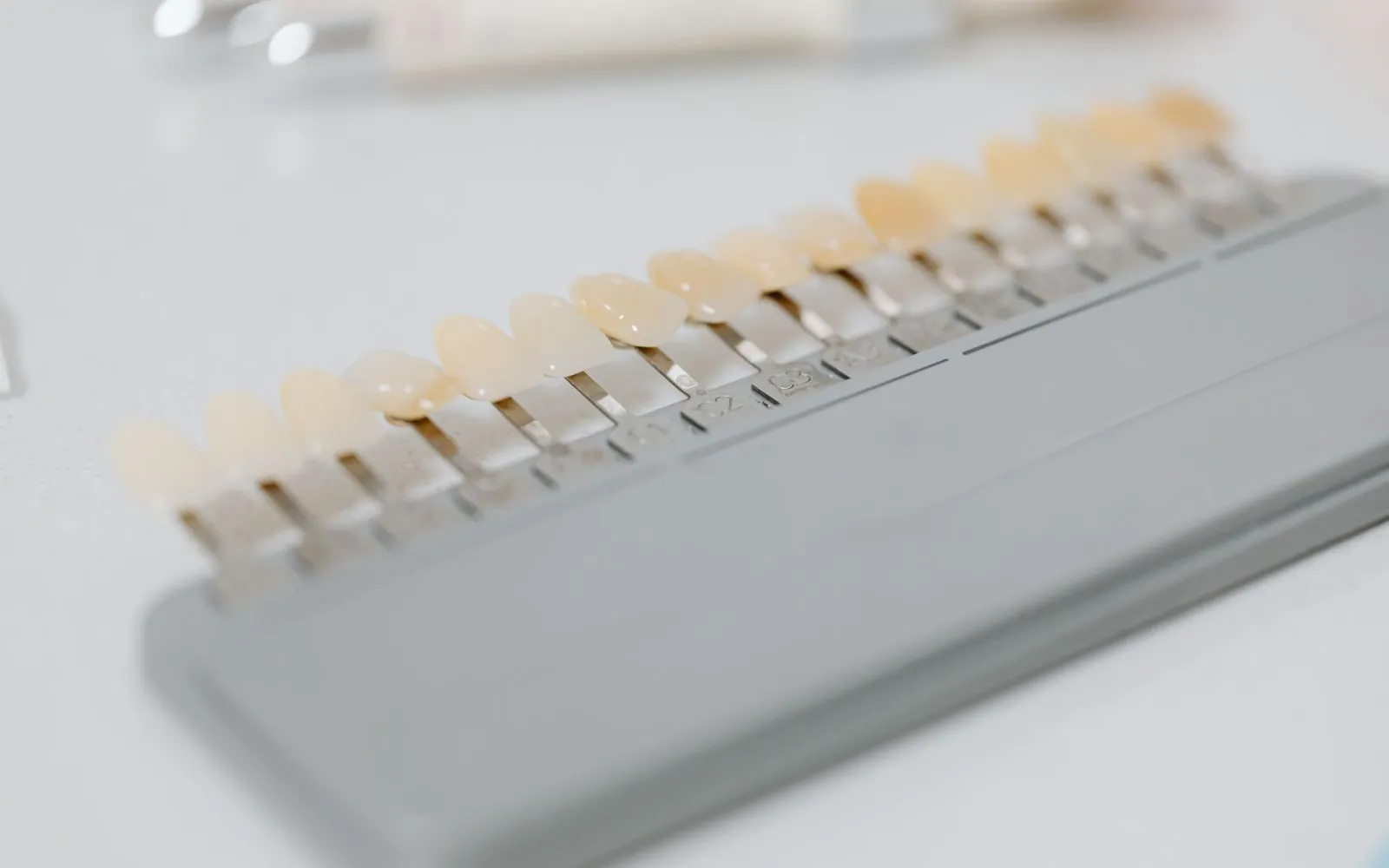 A dental shade guide with a row of sample teeth in different shades on a white surface