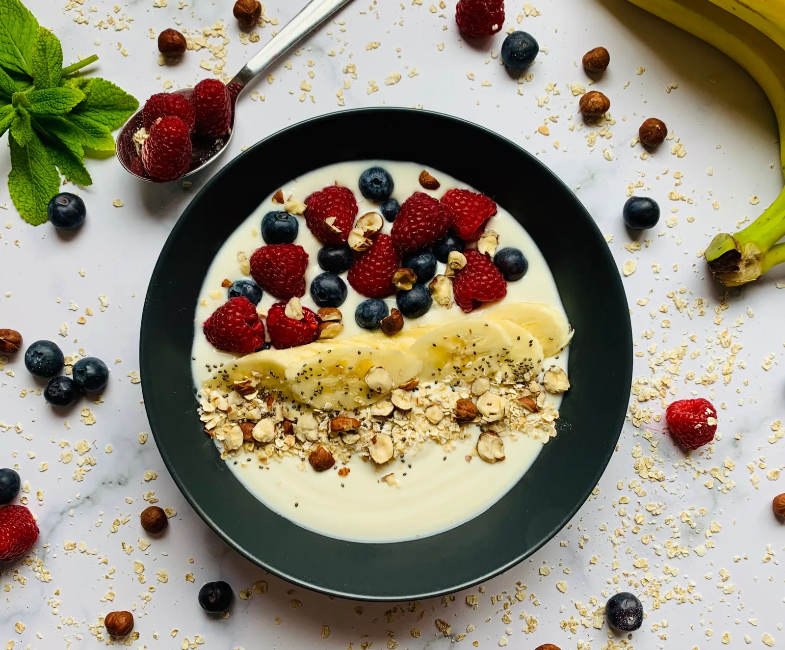 A breakfast bowl topped with berries, banana and nuts.