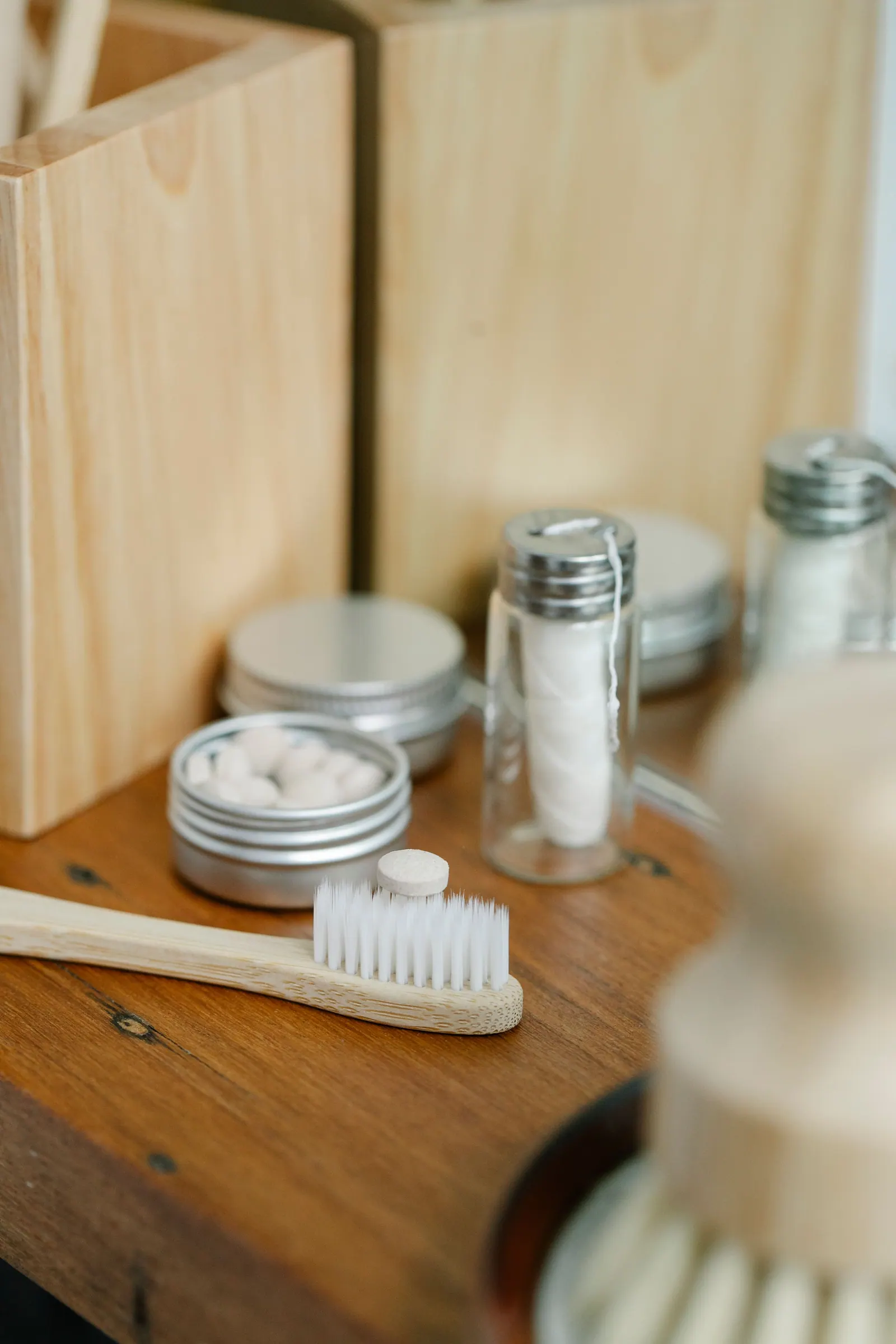 A bamboo toothbrush and oral-care items on a bathroom shelf.