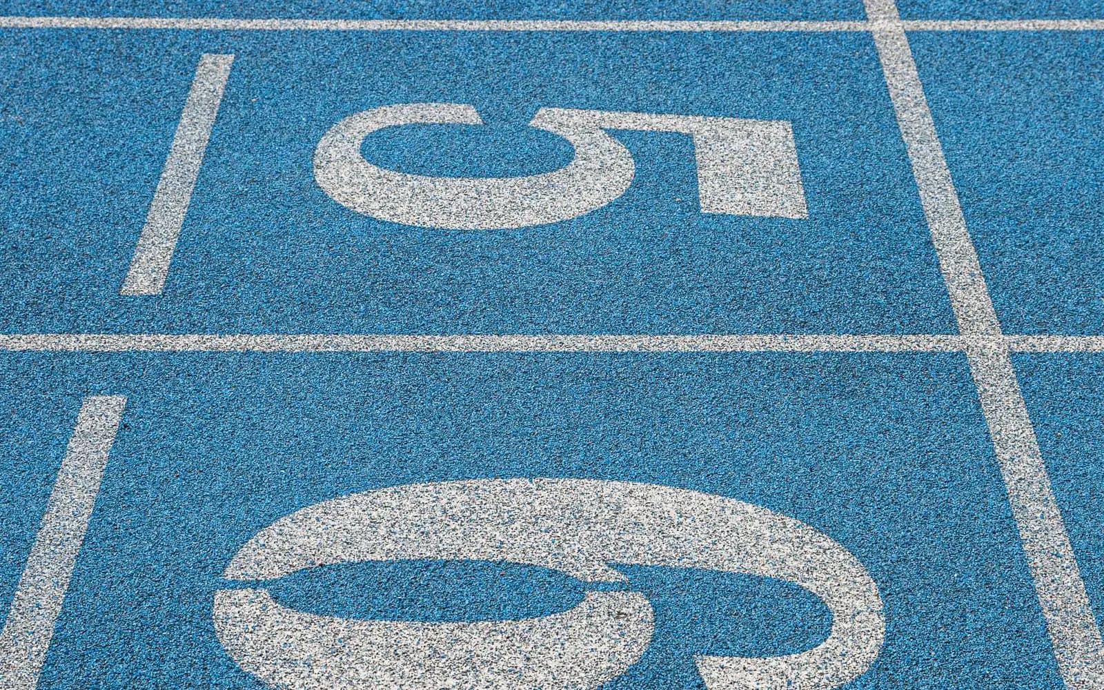 Empty blue running track with white lane numbers at the start line