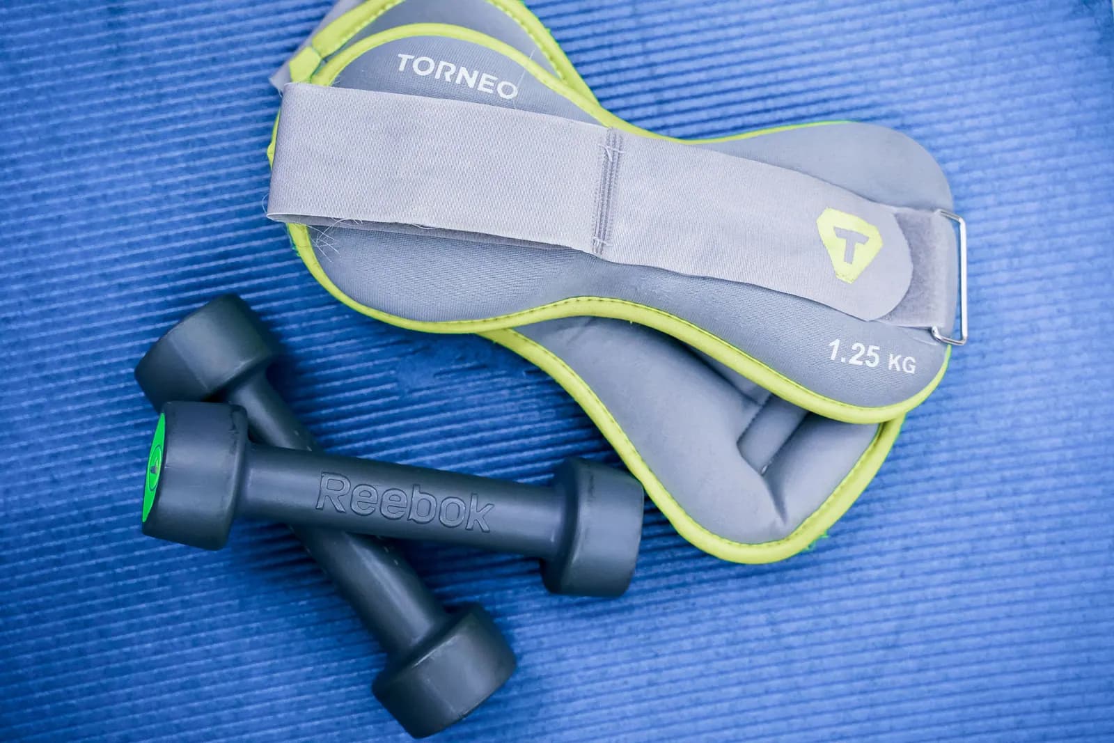 Dumbbells and ankle weights arranged on an exercise mat.
